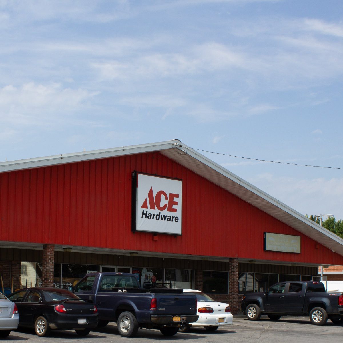 The image depicts a red building with several cars parked in front of it. The building has a sign that reads 